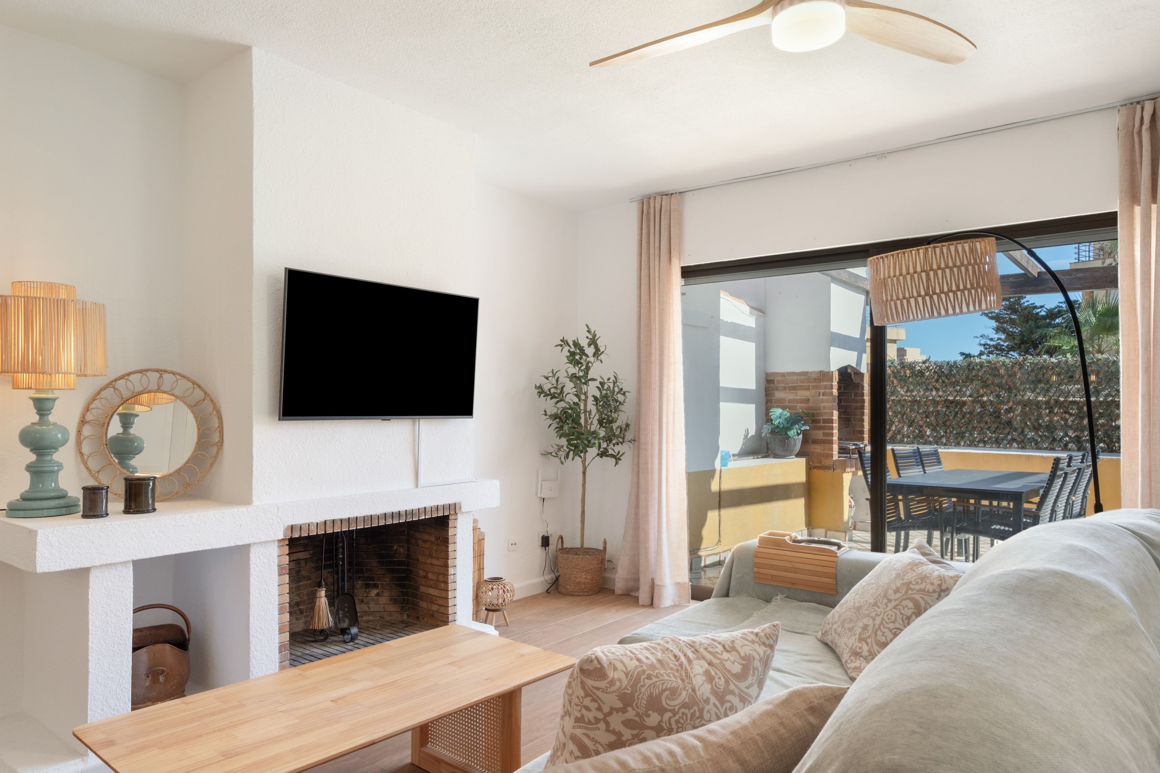 Ein modernes Wohnzimmer mit Kamin, Flachbildfernseher und Blick ins Freie.