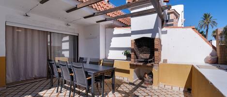 Un patio exterior con una mesa y sillas, una parrilla y vistas del vecindario.