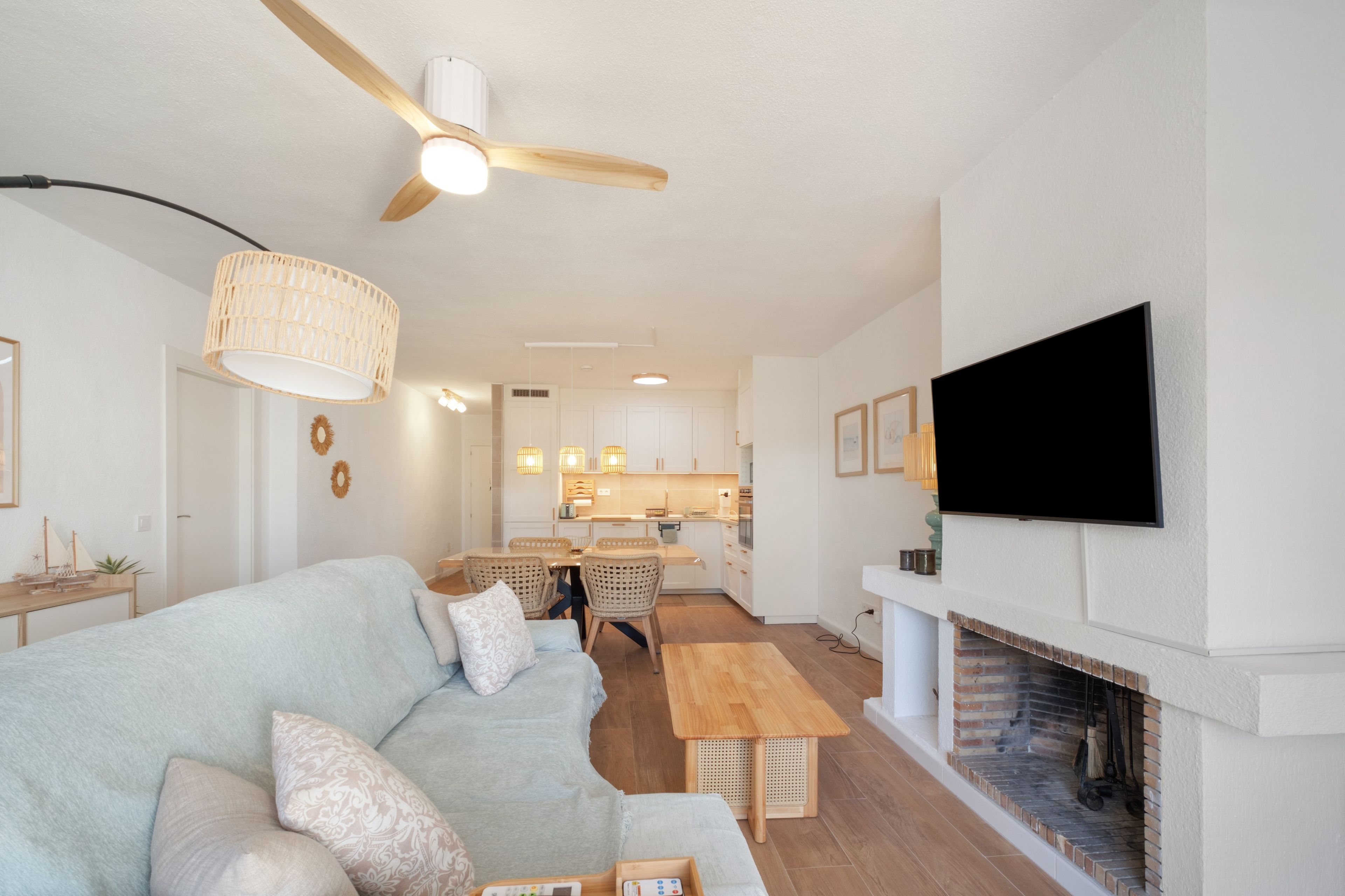 Een moderne woonkamer met een bank, een houten salontafel, een open haard en een aan de muur bevestigde televisie.