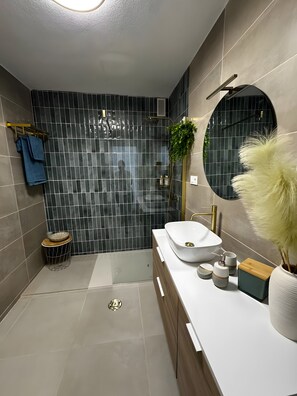 Ein modernes Badezimmer mit großem Spiegel, einem weißen Waschbecken und einer Duschkabine.
