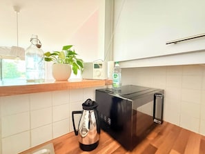 Eine Küche mit Toaster, Wasserkocher, einer Pflanze und einer Wasserflasche auf der Arbeitsfläche.