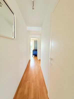 A hallway with wooden flooring leading to a room with a blue cabinet. - Lovely Apartment for 6 Guests with Beautiful Water Views Baby Cot Included (Knokke-Heist)