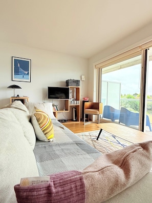 Ein modernes Wohnzimmer mit einer Couch, einem Fernseher, einem Bücherregal und einem Essbereich mit Stühlen.