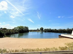 Une rivière bordée d’une plage de sable, d’arbres et sous un ciel dégagé.