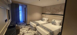 Quarto de hotel com duas camas, carpete estampado com padrão de mármore e vista para um corredor com uma porta.