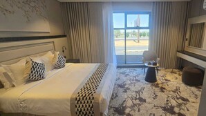 Een hotelkamer met een bed, een klein rond tafeltje, een stoel en uitzicht op buiten.