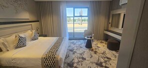Quarto de hotel com cama, mesa redonda pequena, uma cadeira e vista para o exterior.