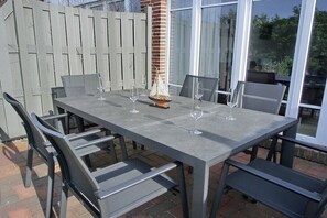 A rectangular outdoor table with four chairs, a small decorative sailboat, and four wine glasses. - Beach Villa Kleckerburg (Langeoog)