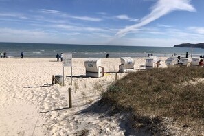 Une plage avec des cabanes de plage numérotées et un ciel dégagé.
