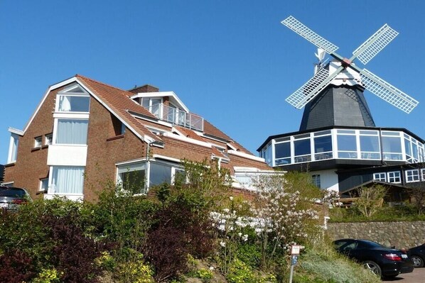 A residential building with a windmill, a car, and a clear blue sky. - Apartment in Laboe with swimming pool (Laboe)