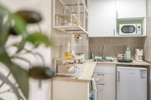 A modern kitchen with white cabinets, a microwave, a sink, and a small refrigerator. - Cozy Studio Apartment in Cala Del Pino with Wi-Fi and Air Conditioning (Cartagena)