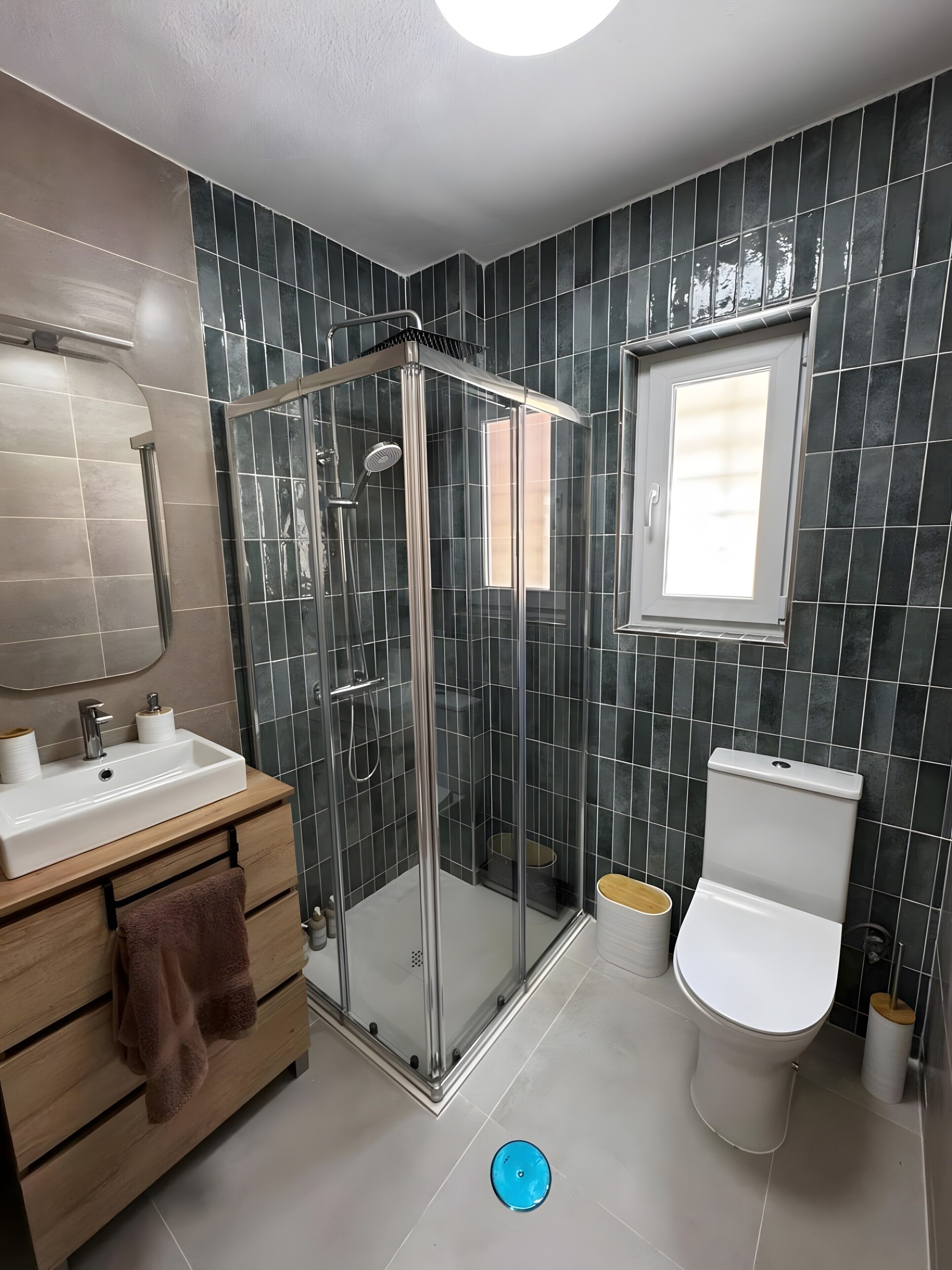 Ein modernes Badezimmer mit einer gläsernen Dusche, einem weißen Waschbecken und einer Toilette.