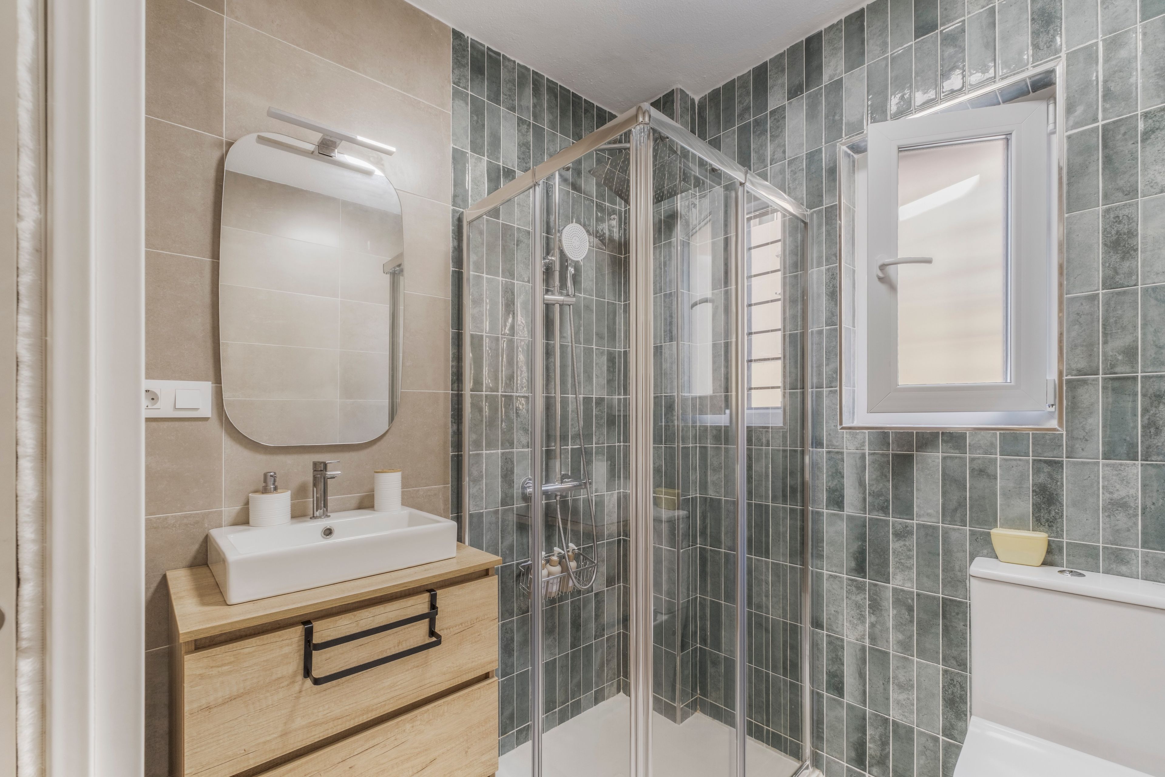 Une salle de bain moderne avec une douche à parois de verre, un lavabo blanc et un miroir au-dessus.