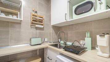 A modern kitchen with a microwave, a kettle, and a kettle holder on the countertop.