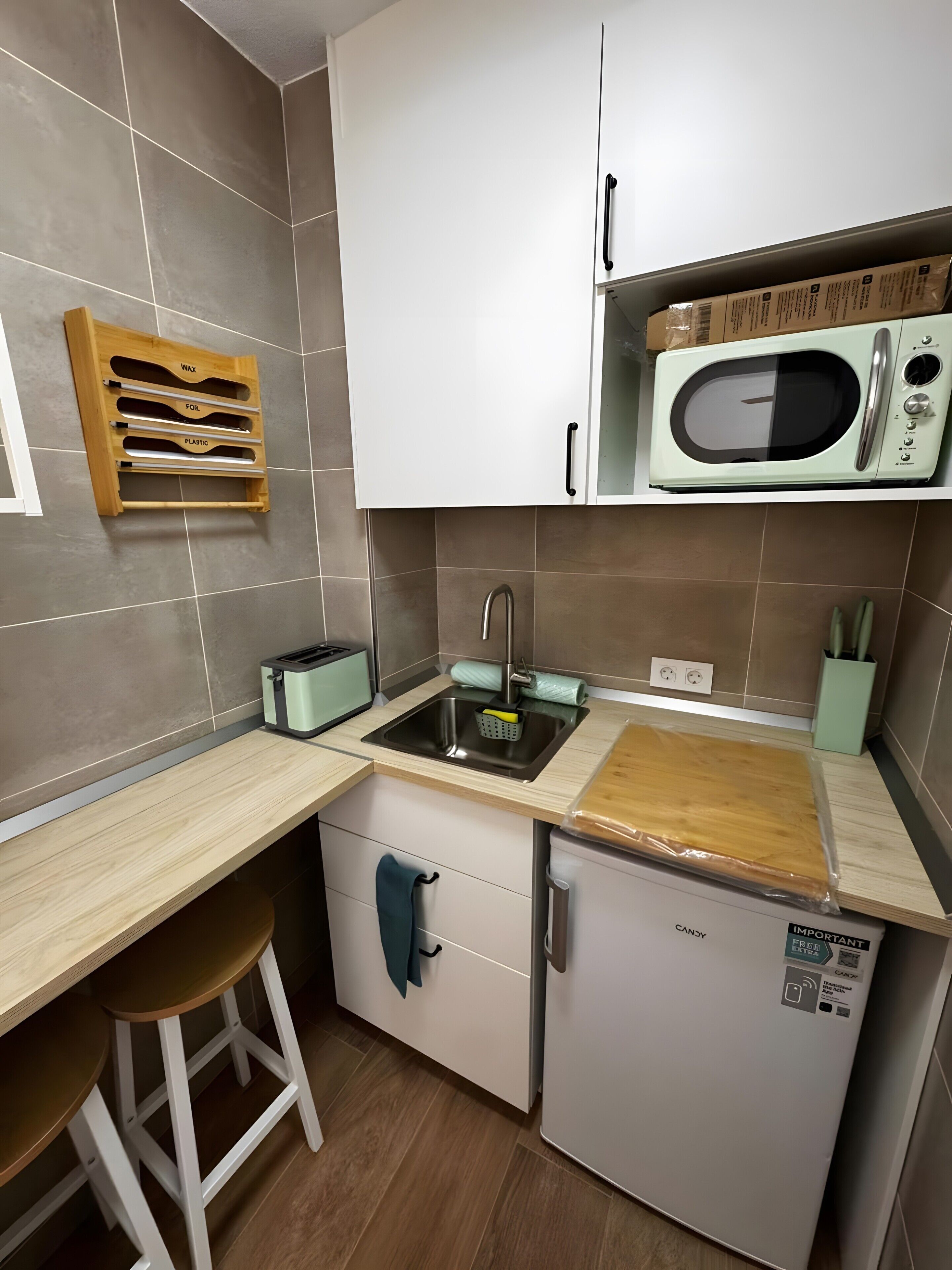 Eine kompakte Küche mit Mikrowelle, Toaster und kleinem Kühlschrank.