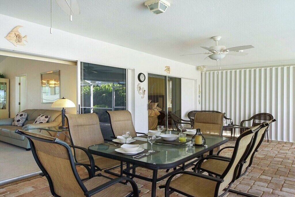 Un coin repas avec une table en verre, des chaises et un ventilateur de plafond.