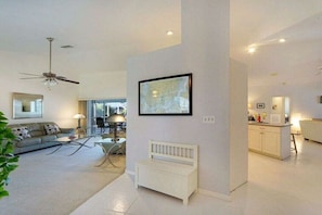 A modern living room with a sofa, a white bench, a ceiling fan, and a framed map on the wall. - CCVS - Bimini Sunset (Cape Coral)