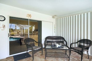 A balcony with wicker furniture, a glass table, and a pool view. - CCVS - Bimini Sunset (Cape Coral)
