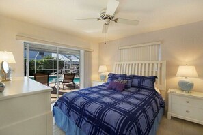 Ein Schlafzimmer mit einem Bett, Nachttischen, einem Deckenventilator und Blick auf einen Pool.