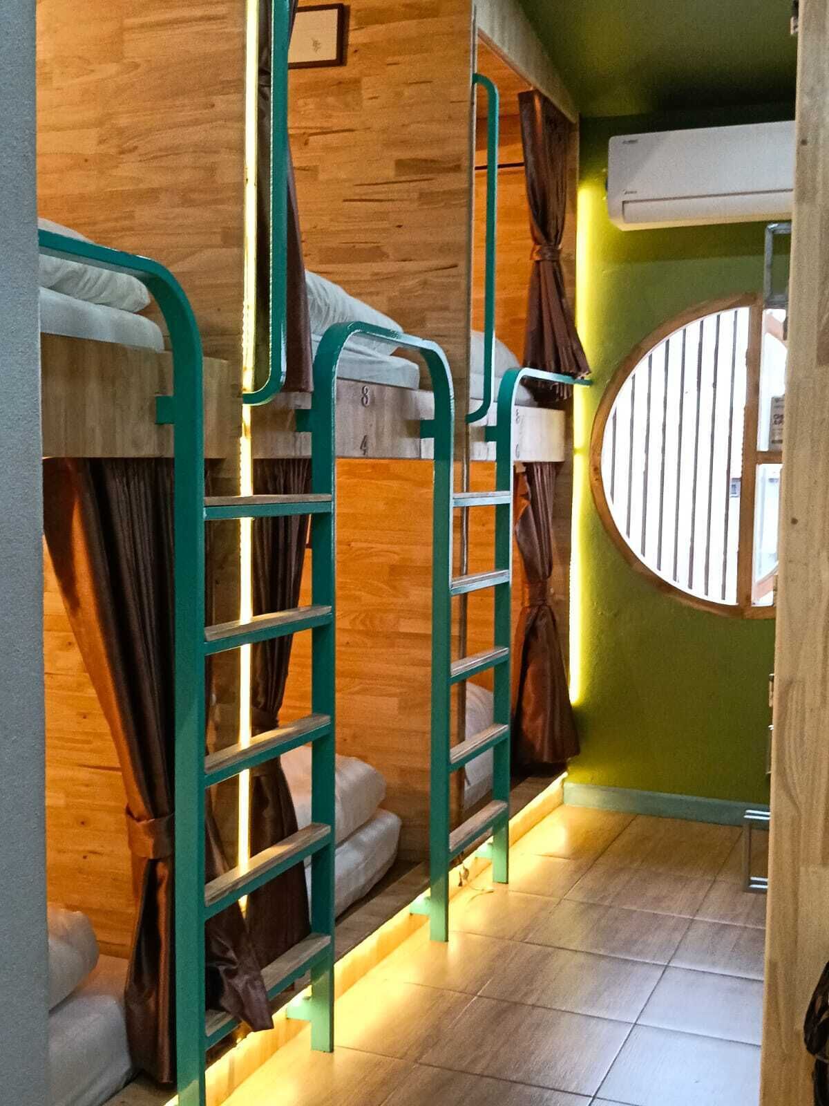 Quarto com beliche, escada, cortinas e janela com grades.