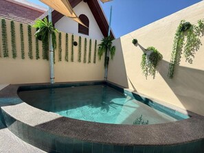 A swimming pool with a curved edge, surrounded by walls with hanging plants. - La Vida Hostel Chiang Mai (Mueang Chiang Mai)