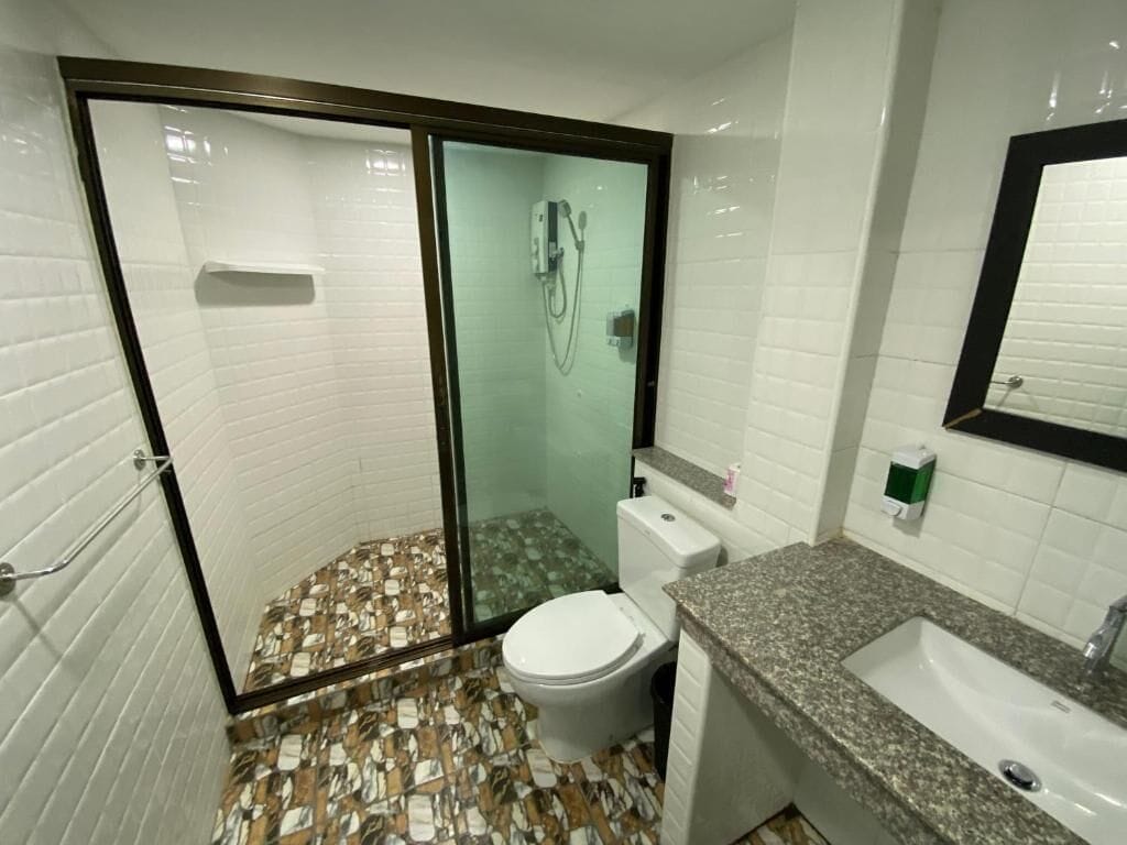 A bathroom with a glass-enclosed shower, a toilet, and a sink with a granite countertop.