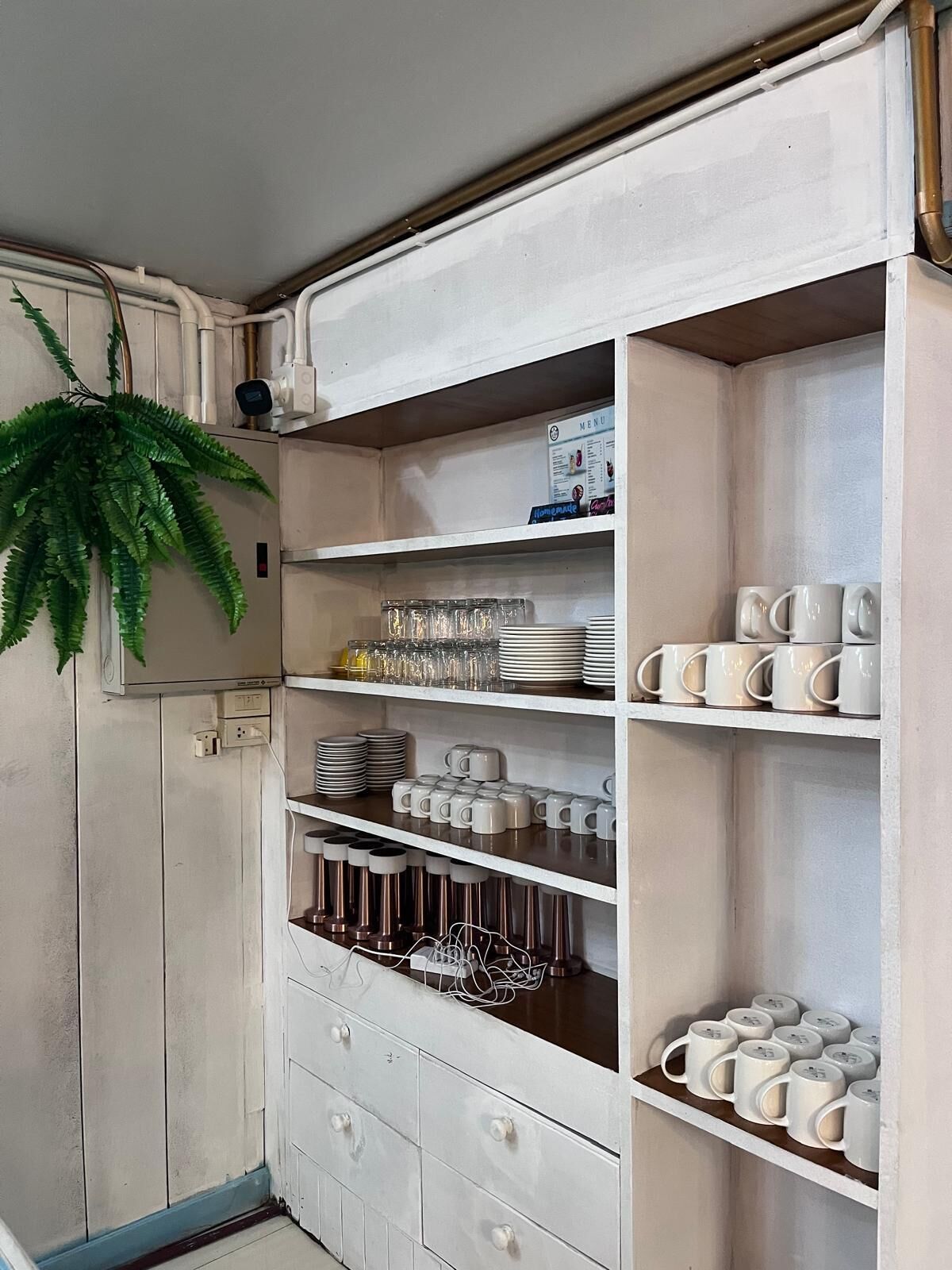 Un mueble blanco con varios estantes que contiene tazas, platos y vasos.