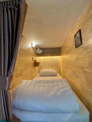 Una habitación pequeña con una cama, una lámpara de pared y un marco de cuadro.