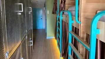 Un pasillo con literas, un dispensador de agua y una puerta que da a otra habitación.