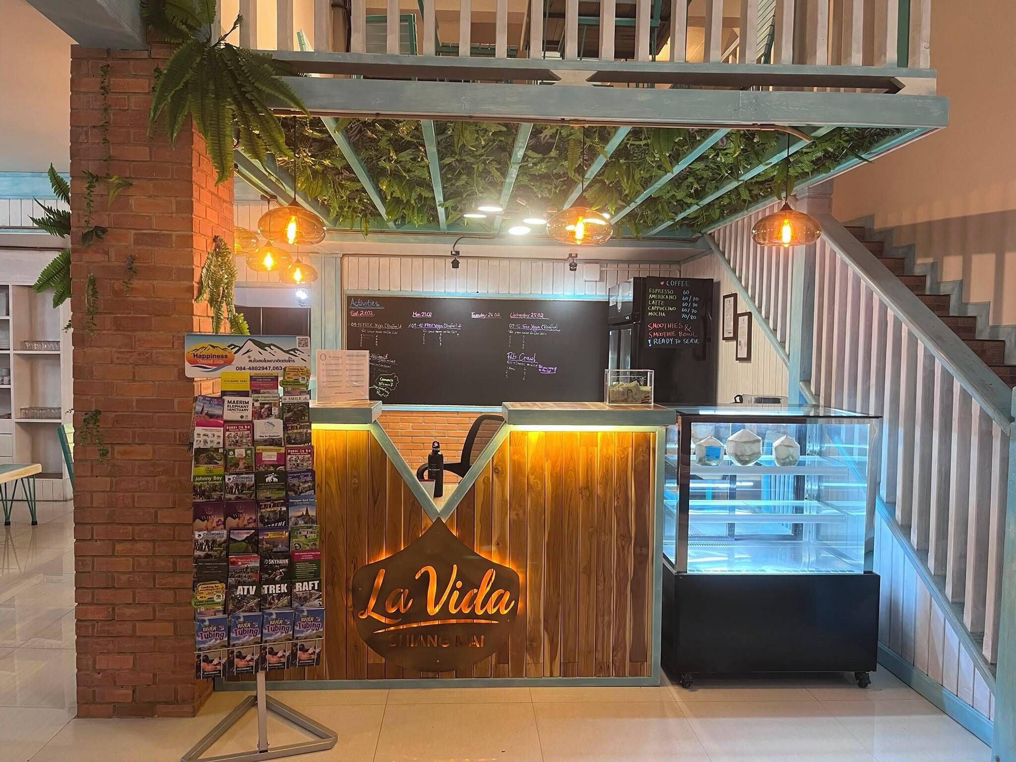 Un café appelé « La Vida », avec un comptoir en bois, un tableau affichant le menu et un escalier sur la droite.