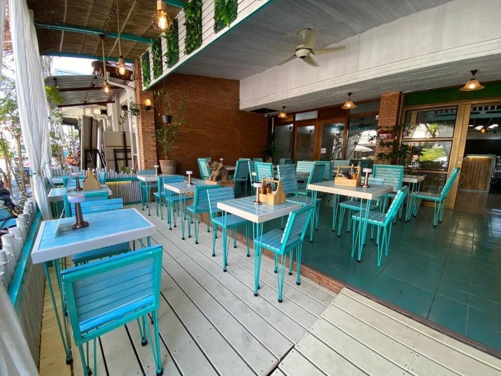 An outdoor seating area with tables and chairs, a ceiling fan, and potted plants.