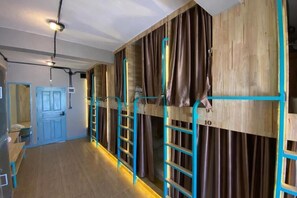 Habitación de hotel con literas, una puerta de madera y un baño con puerta azul.