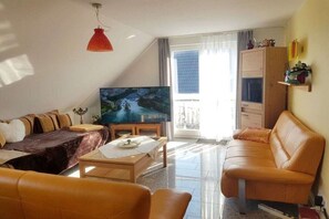 Een woonkamer met een bank, een salontafel en een televisie.