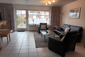 A living room with a sofa, armchair, coffee table, and a dining table. - Pennekamp Carolinensiel (Carolinensiel)
