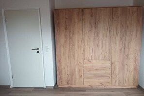 A room with a white door and a wooden wardrobe with multiple compartments. - Pennekamp Carolinensiel (Carolinensiel)