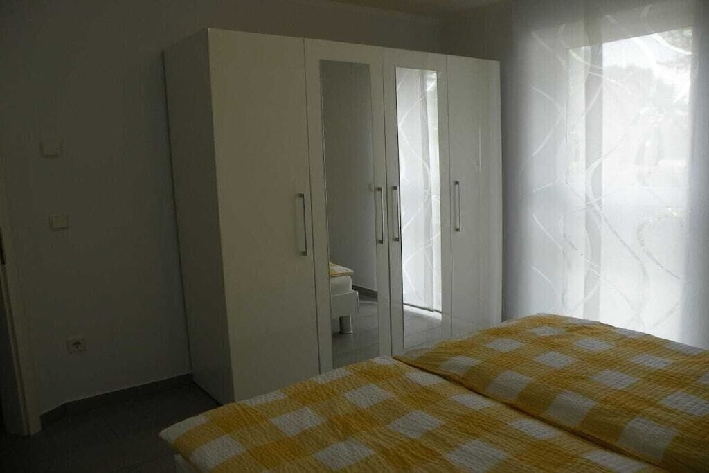 A bedroom with a bed, a wardrobe, and a window with curtains.