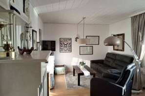 A living room with a sofa, a coffee table, and a lamp. There is a rug on the floor and a plant on the coffee table. - with dike and North Sea view North Beach (Nordstrand)