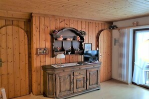 Ein Zimmer mit Holzwänden, einem Holzschrank mit Flachbildfernseher und einem kleinen Tisch mit Lampe.