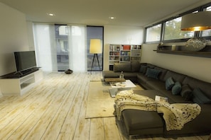 A modern living room with a sofa, a coffee table, a bookshelf, and a television.