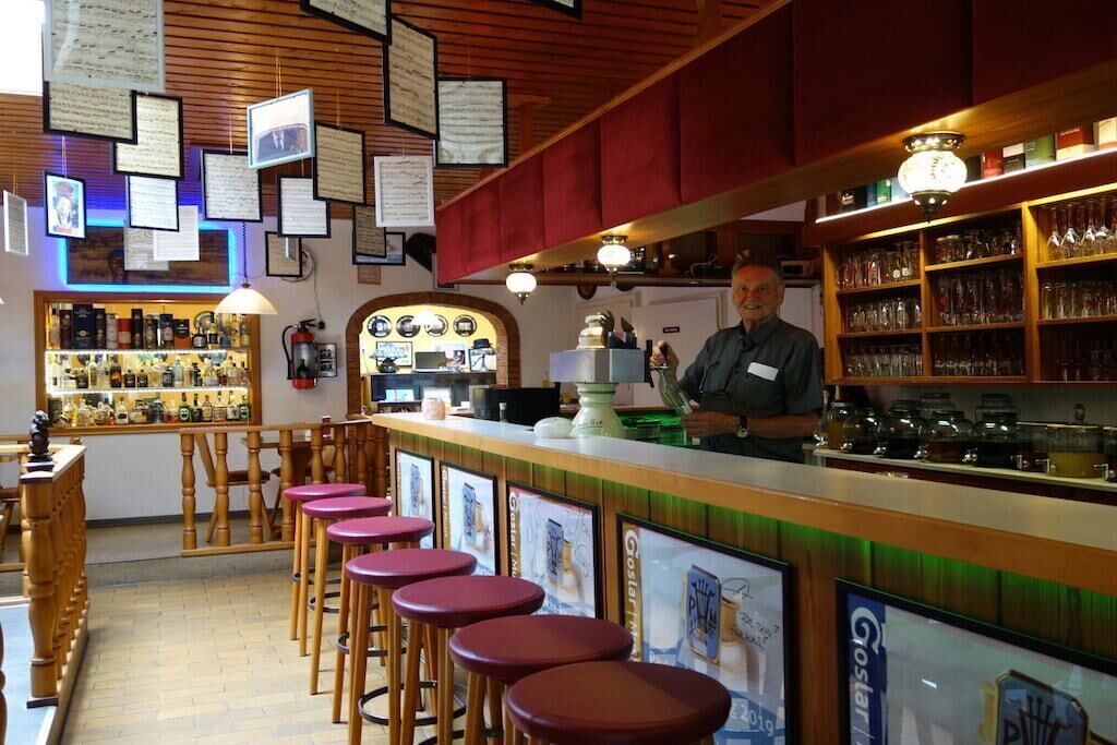 A bar area with stools, a counter, and shelves with bottles.