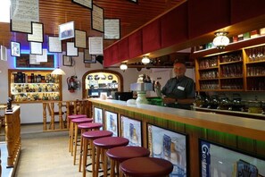 Un espace bar avec des tabourets, un comptoir et des étagères remplies de bouteilles.