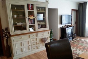 A living room with a white cabinet, a television, and a patterned rug. - Holiday apartment with 2 bedrooms (Goslar\/Hahnenklee)