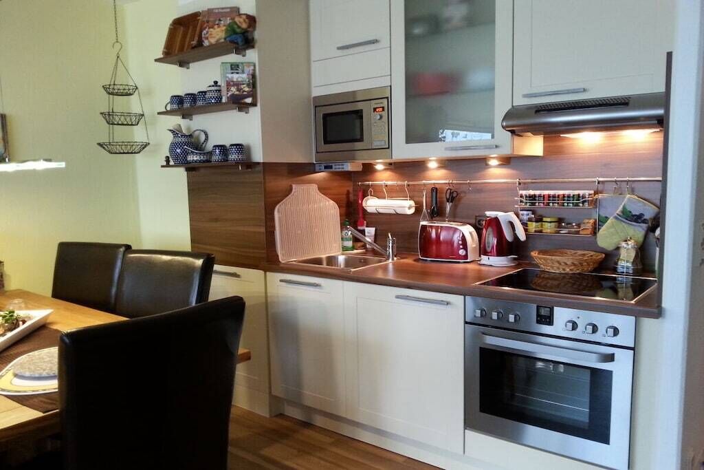 A compact kitchen with white cabinets, a microwave, an oven, and a sink.