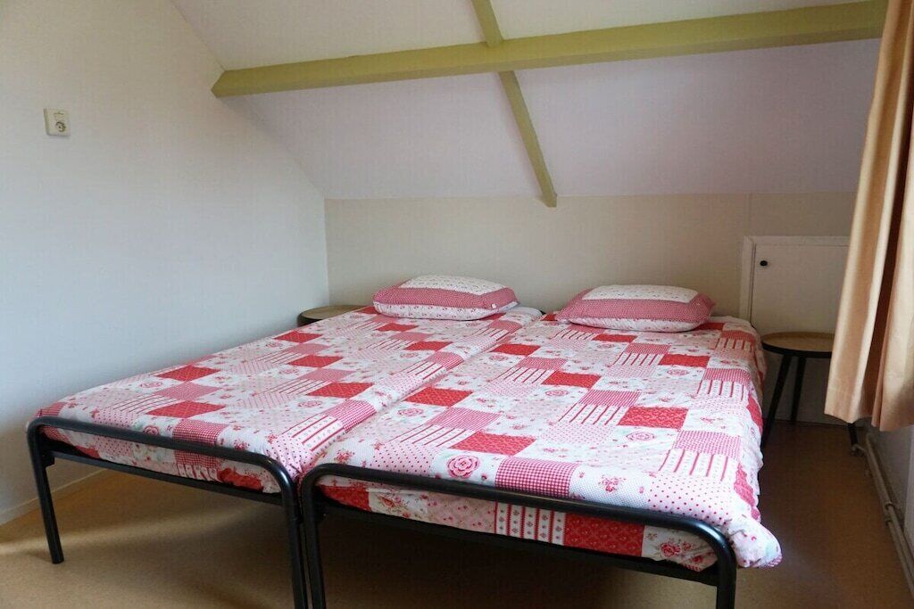 A single bed with a quilted cover, a bedside table, and a wardrobe in a room with a sloped ceiling.
