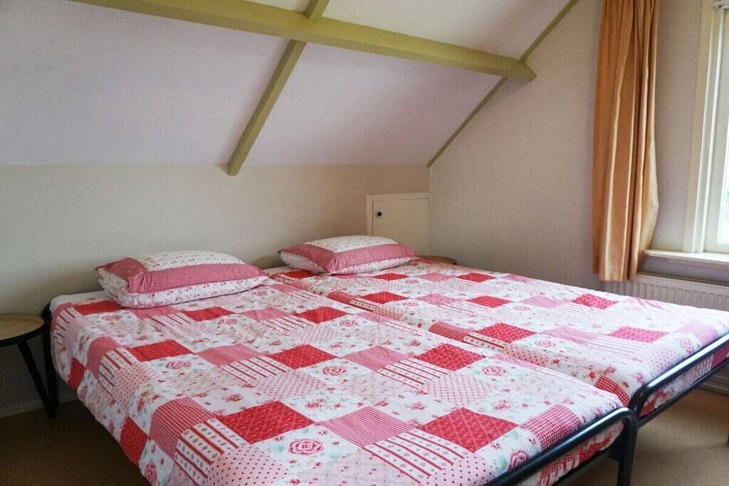 Un dormitorio con una cama, una mesita de noche, una ventana con cortinas y un radiador.