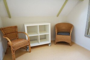 A room with a white shelving unit, two wicker chairs, and a small table. - Holiday home in Breezand with swimming pool (Breezand)