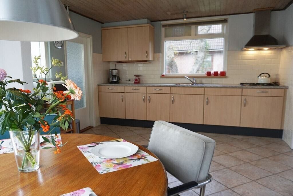 A kitchen with wooden cabinets, a window, and a dining table with a chair.