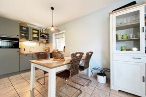 A kitchen with a dining table, chairs, cabinets, and a hanging light fixture. - Holiday apartment with 1 bedroom (Dierhagen)
