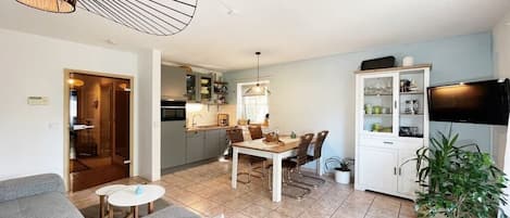 A modern living room with a sofa, a dining table, and a kitchen in the background.