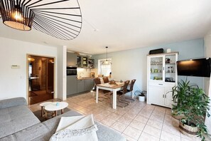 Ein modernes Wohnzimmer mit einer Couch, einem Esstisch und einer Küche im Hintergrund.